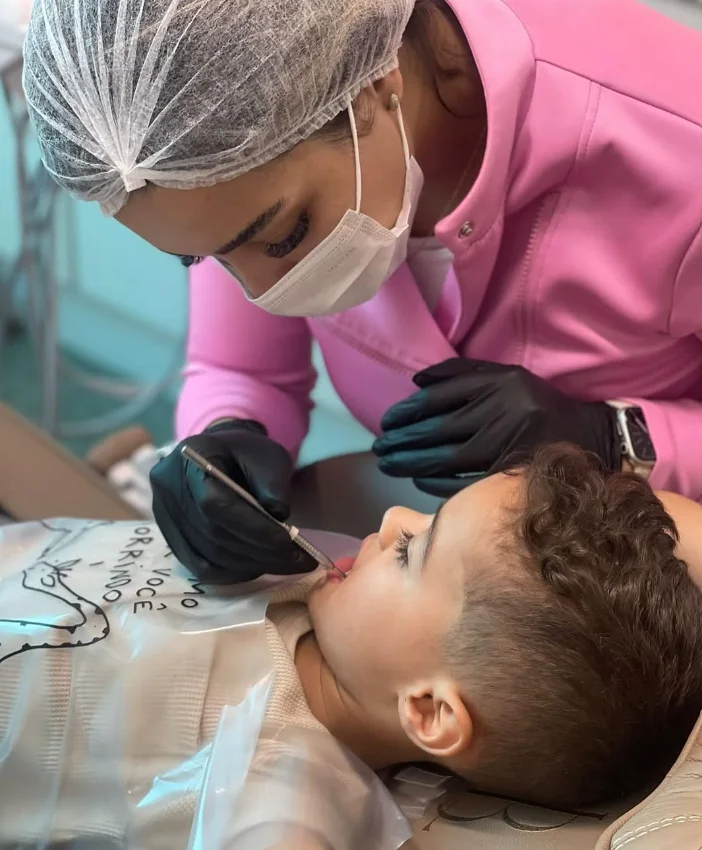 Dra. Barbara Lesley examinando os dentes de uma criança em atendimento de odontopediatria